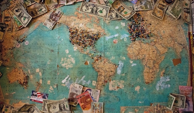 A map on a wall with money and pins used for planning a trip