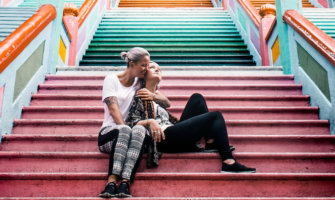 Two lesbian tarvel bloggers posing a a colorful set of stairs in Asia