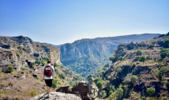 Nomadic Matt hiking solo in Africa over a rugged cliff