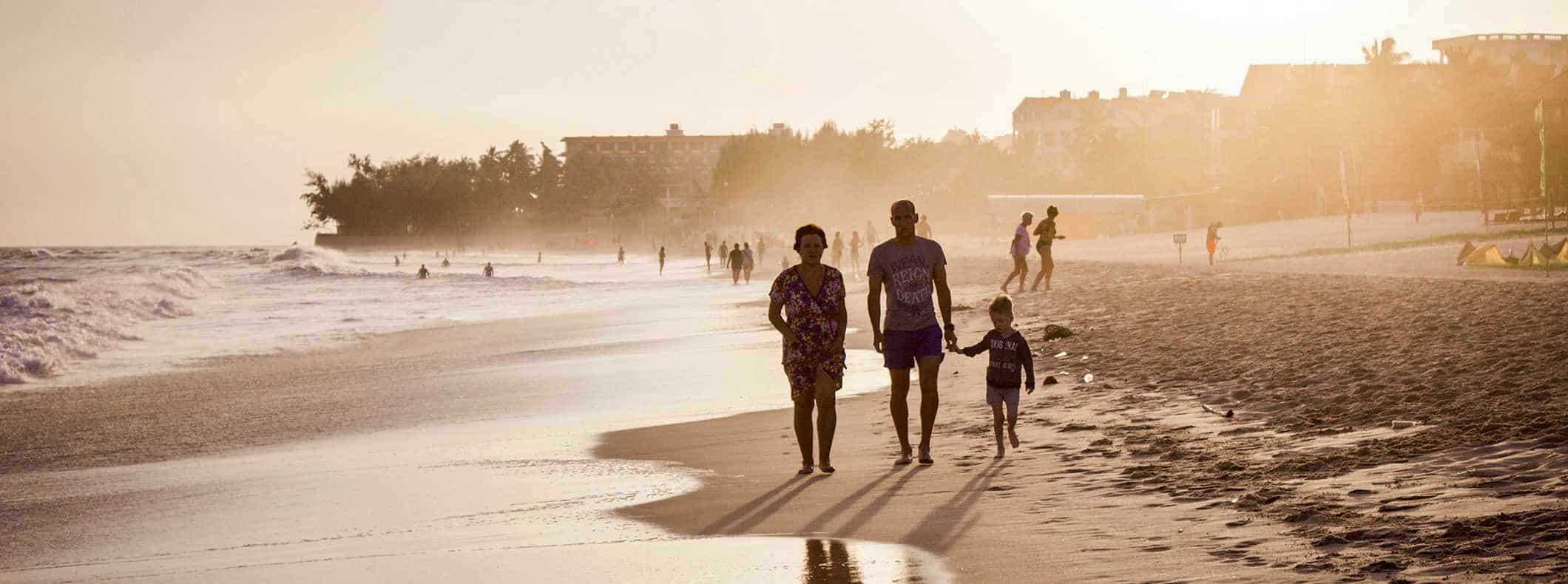 A family walking a wide beach in a tropical destination