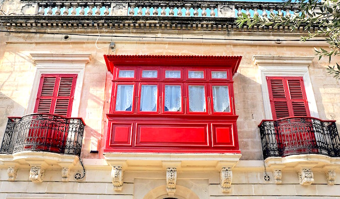 beautiful building facade and bright red shutters in malta