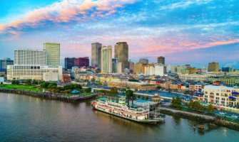 The skyline of New Orleans as seen from above the water, featuring an old steamboat