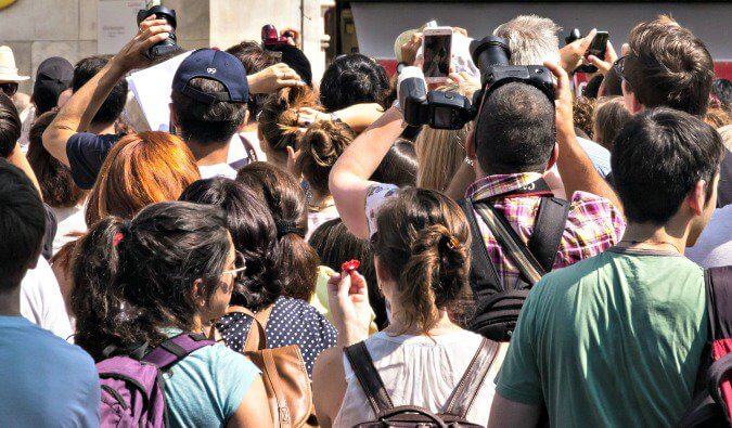 many people in a crowd photographed from behind many holding up cameras and mobile phones some at the back unable to see