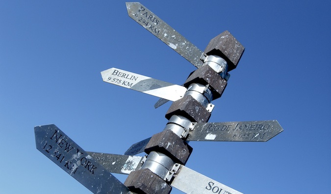 Signs pointing in all directions on a tall sign post with a blue sky as the background