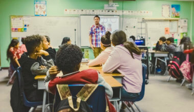 A man teaching English to a classroom of students abroad