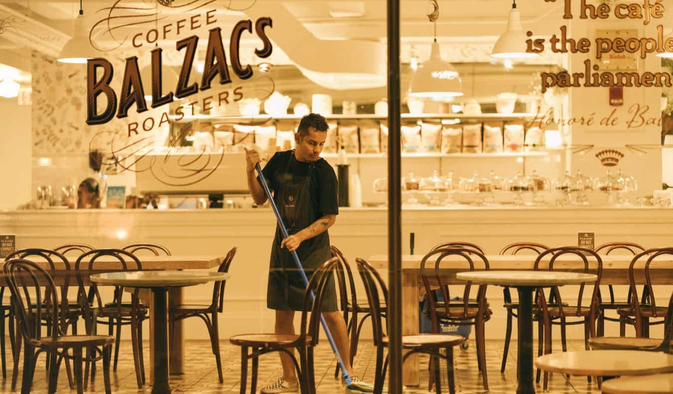 A young male worker mopping the floor at a cafe and restaurant at night