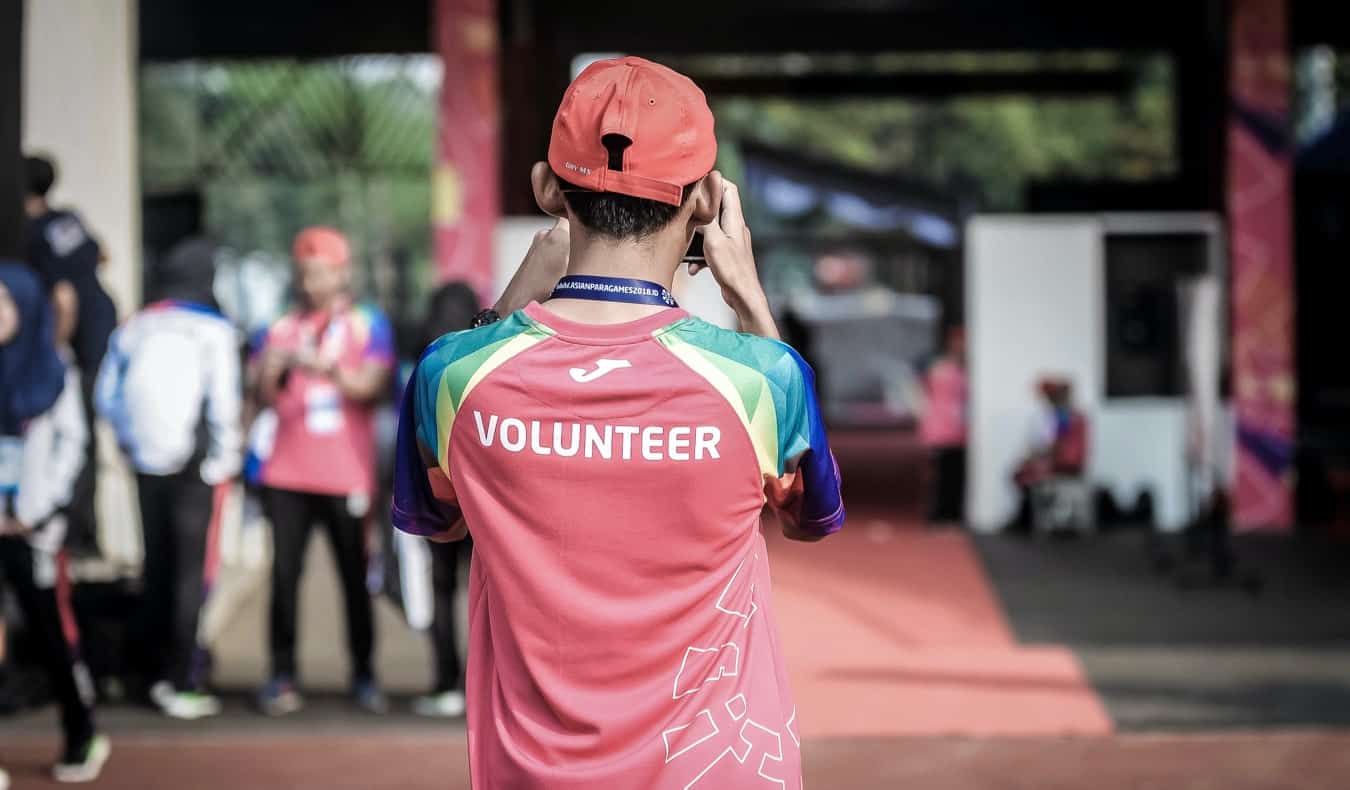A young male volunteering at a large public event during the summer