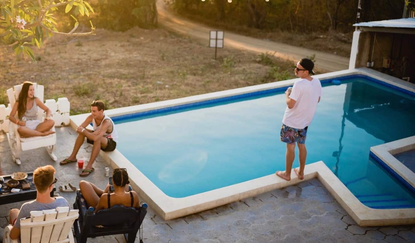 A group of travelers hanging out at the pool at a hostel overseas